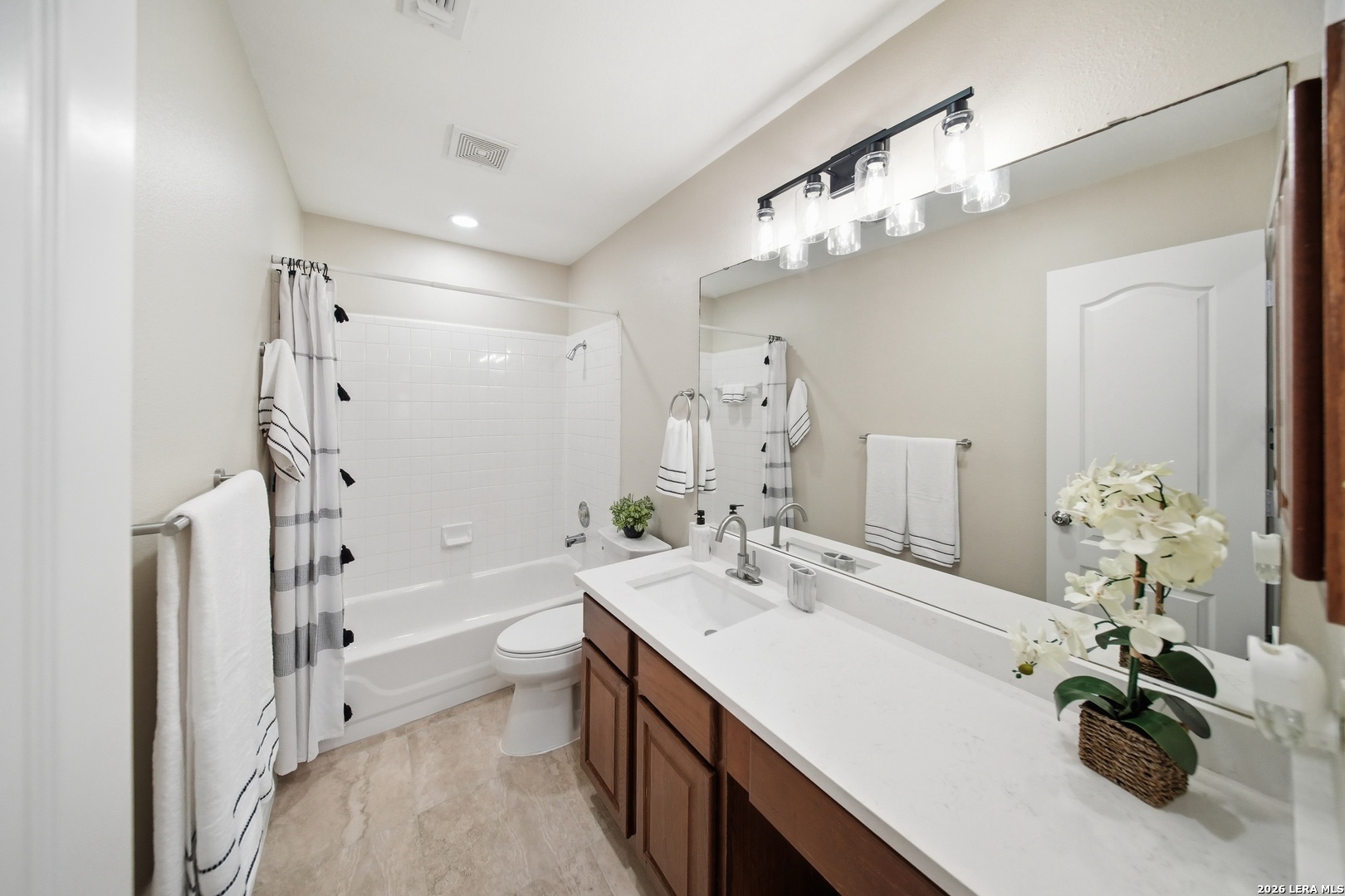 5607 Spring Quail San Antonio, TX 78247 - Photo 20 of 25 a bathroom with a double vanity sink a toilet a mirror and shower