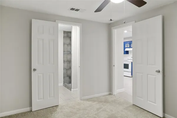 an empty room with closet and a chandelier fan