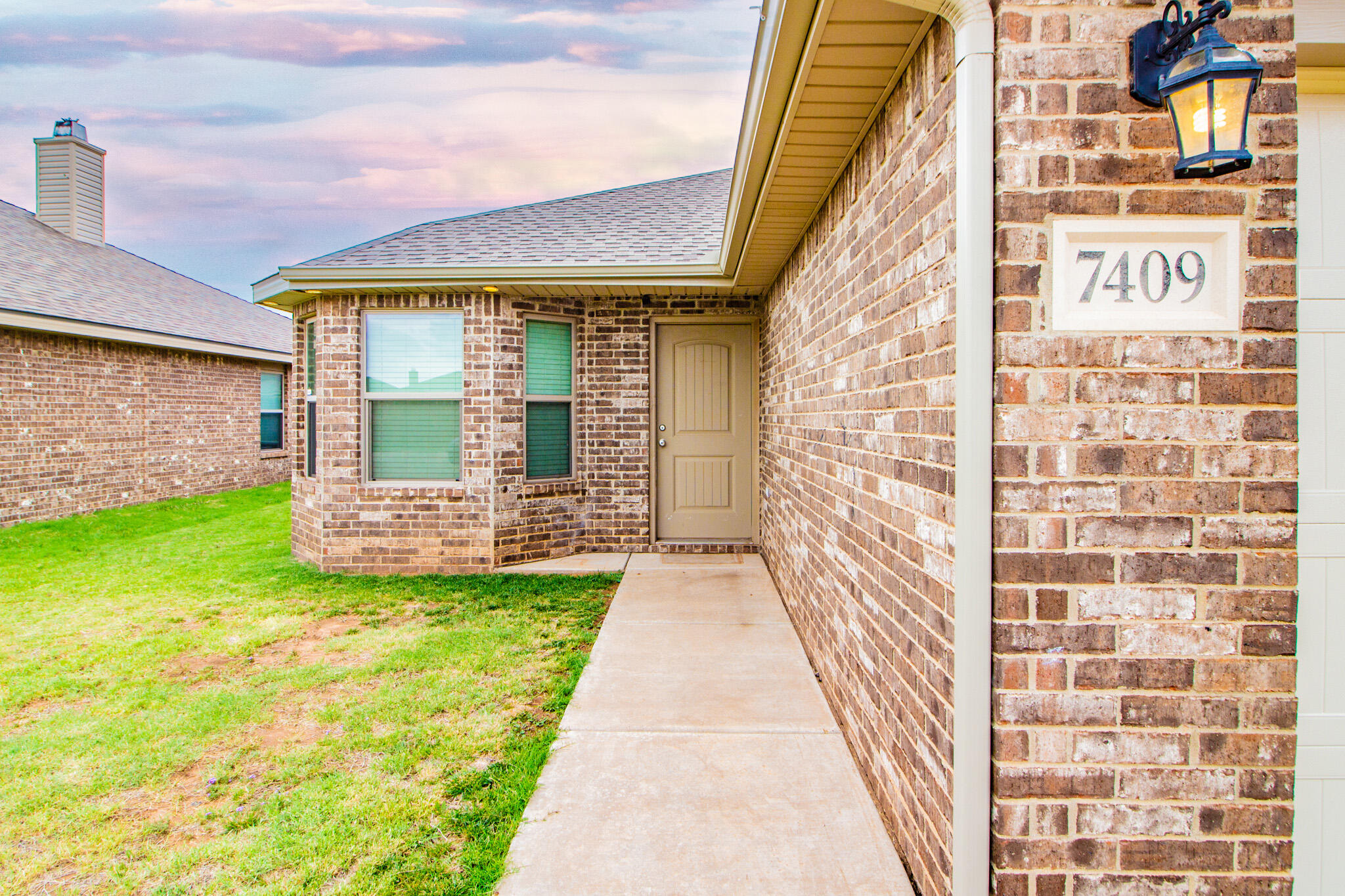 7409 101st Street Lubbock, TX 79424 - Photo 2 of 22 a view of a brick house with a yard