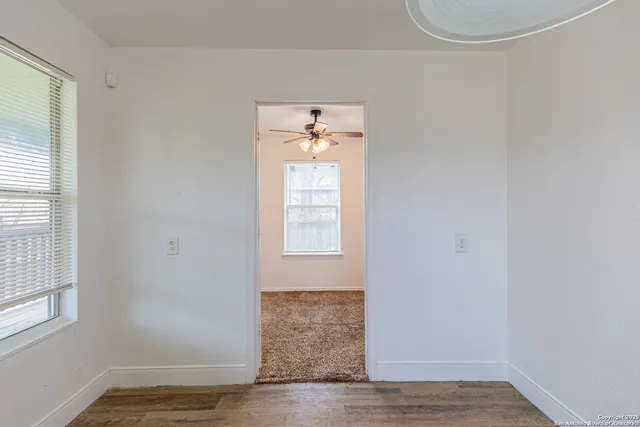 a view of a hallway with wooden floor and a window