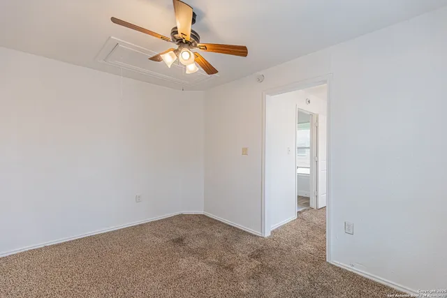 an empty room with a chandelier fan and a ceiling fan