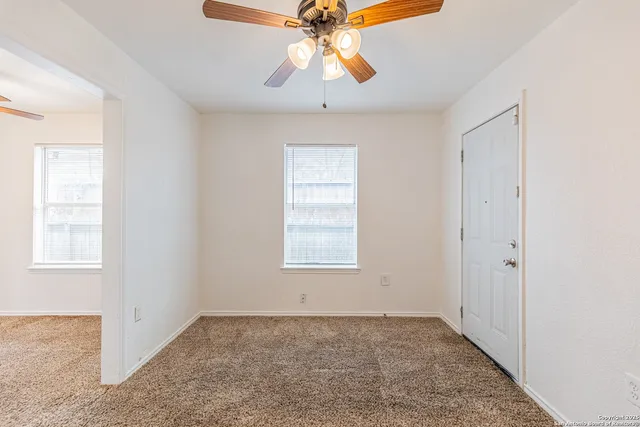 a view of an empty room and window and chandelier fan