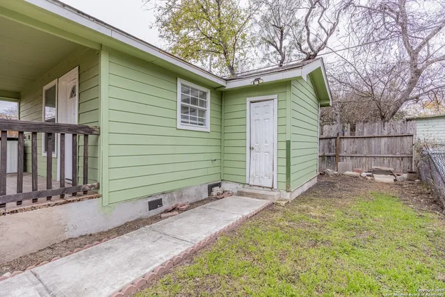 a small white house with a small yard and plants