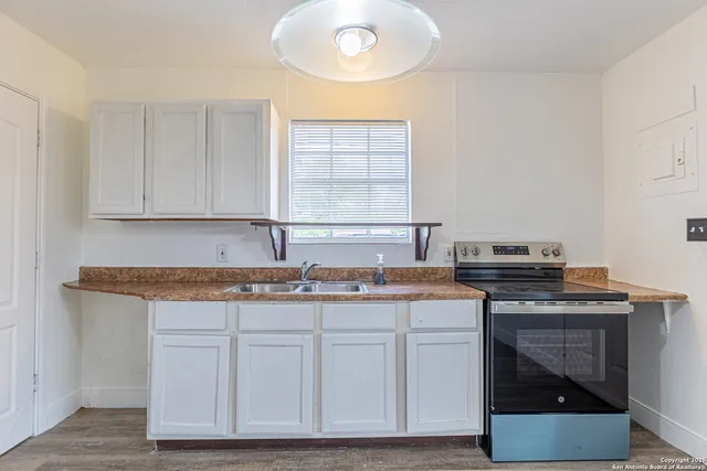 a kitchen with granite countertop a sink stove and cabinets