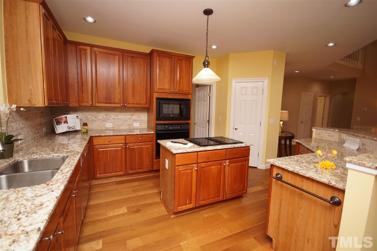 12520 Amoretto Way Raleigh, NC 27613 - Photo 8 of 25 a kitchen with granite countertop wooden cabinets and white appliances