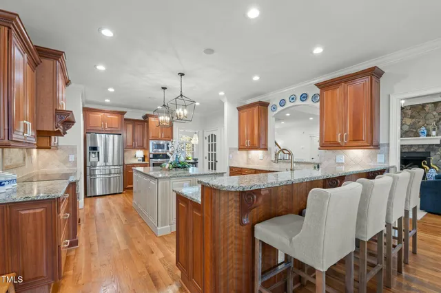 a kitchen with kitchen island granite countertop a table chairs refrigerator and microwave