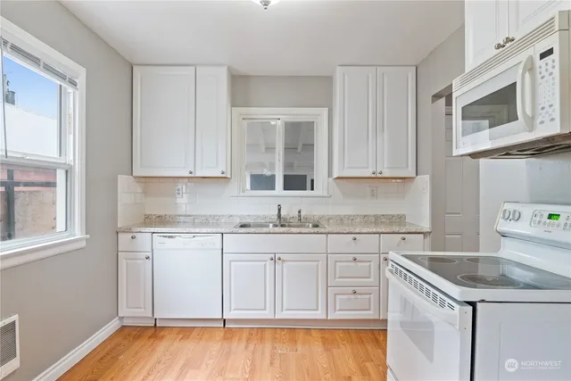a kitchen with granite countertop cabinets stainless steel appliances a sink and a window