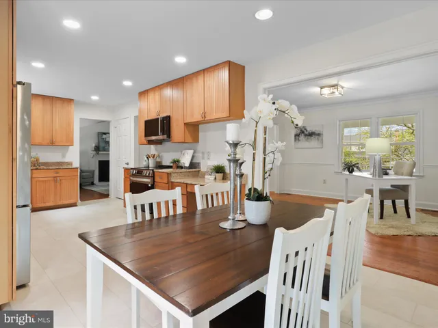 a kitchen with stainless steel appliances granite countertop a table chairs and a refrigerator