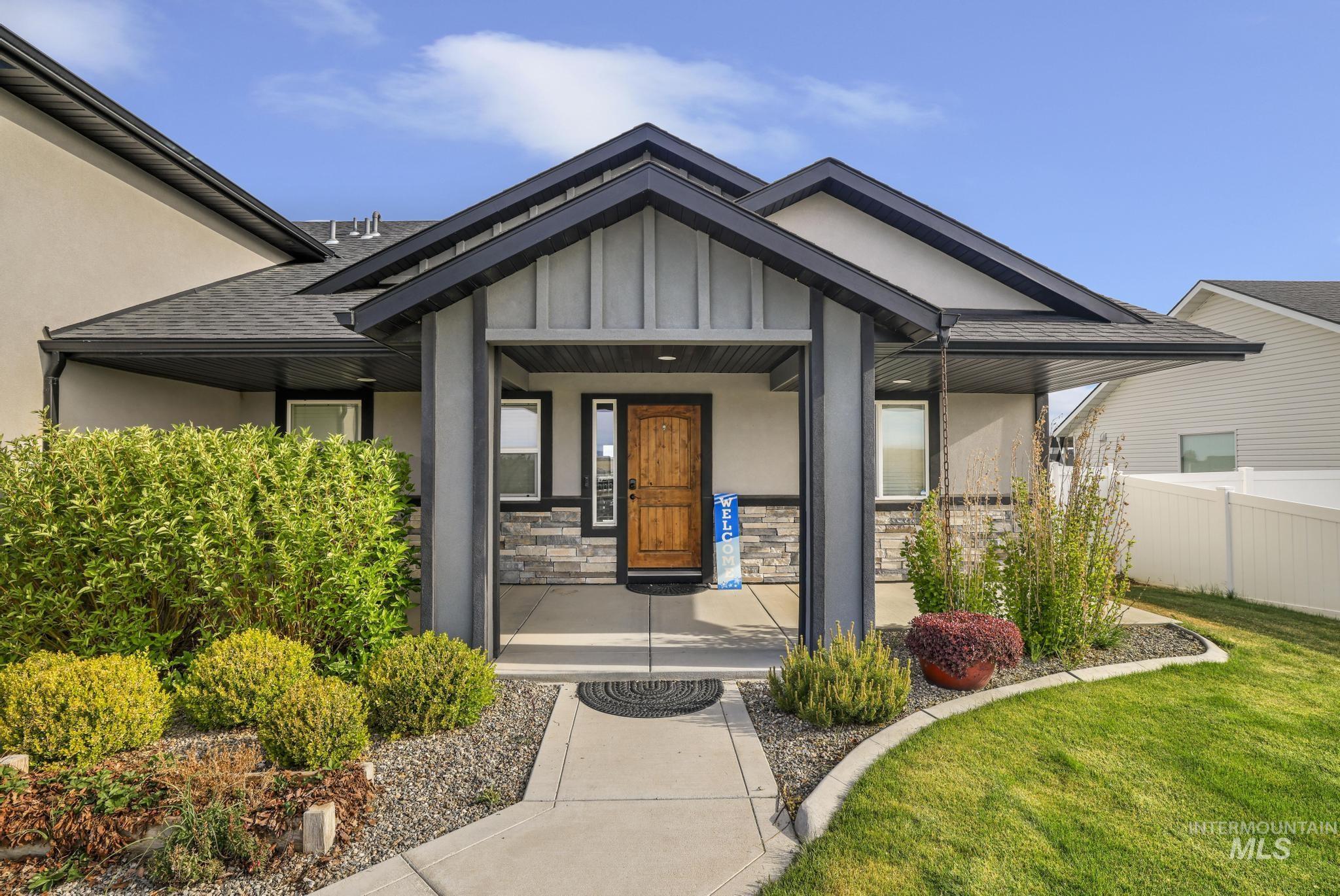Front exterior featuring a covered entry, wood-finish entry door, and stone facade accents