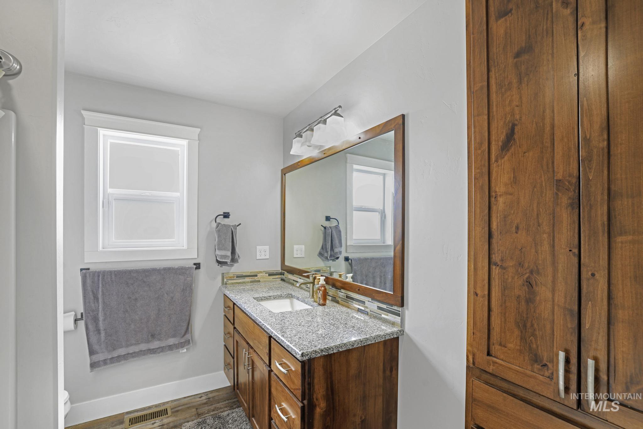 1150 Kimberly Meadows Road Kimberly, ID 83341 - Photo 12 of 32 Bathroom vanity featuring a granite countertop, undermount sink, and wood-finish cabinetry