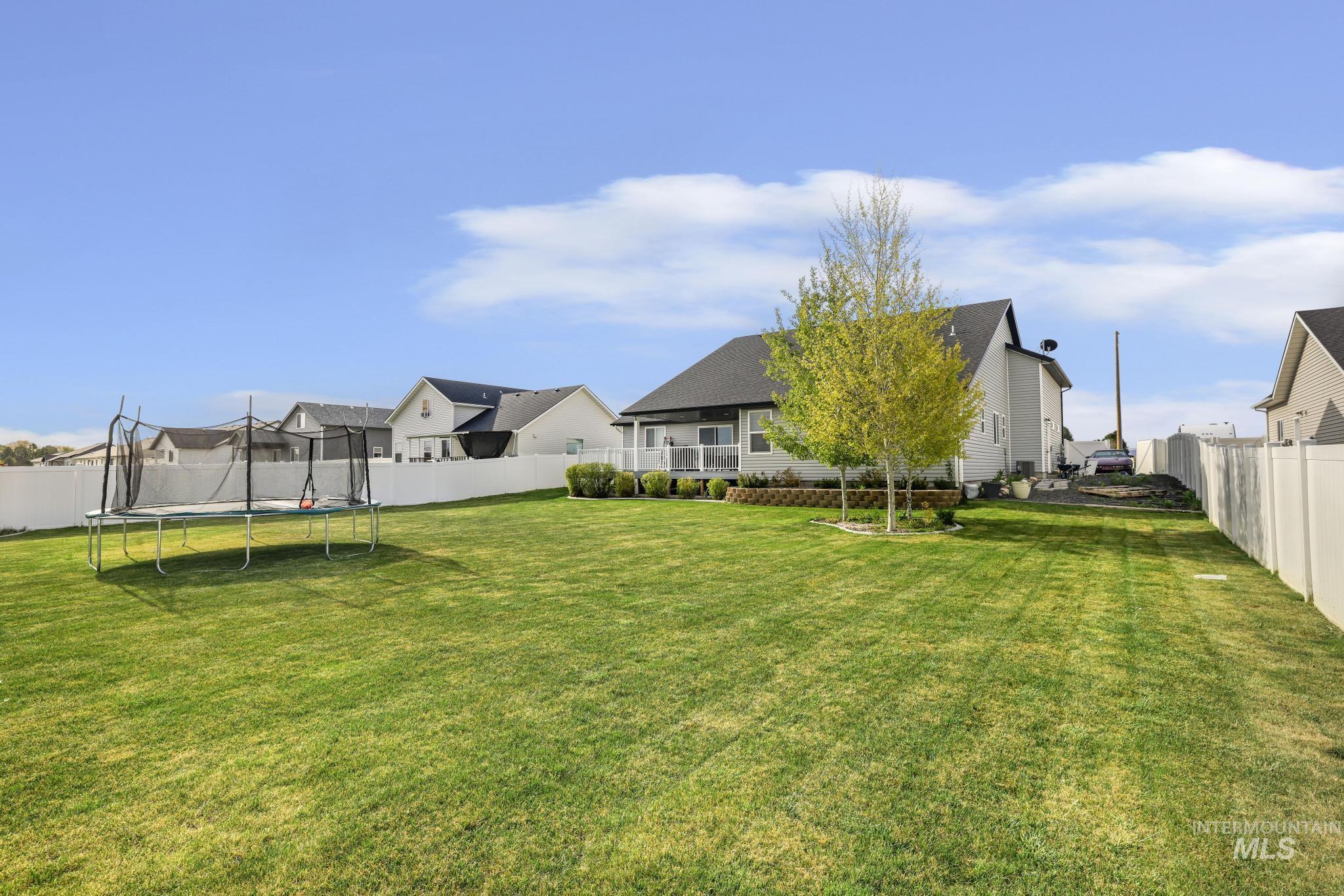 1150 Kimberly Meadows Road Kimberly, ID 83341 - Photo 27 of 32 Expansive rear yard featuring a manicured lawn, established trees, and white privacy fencing