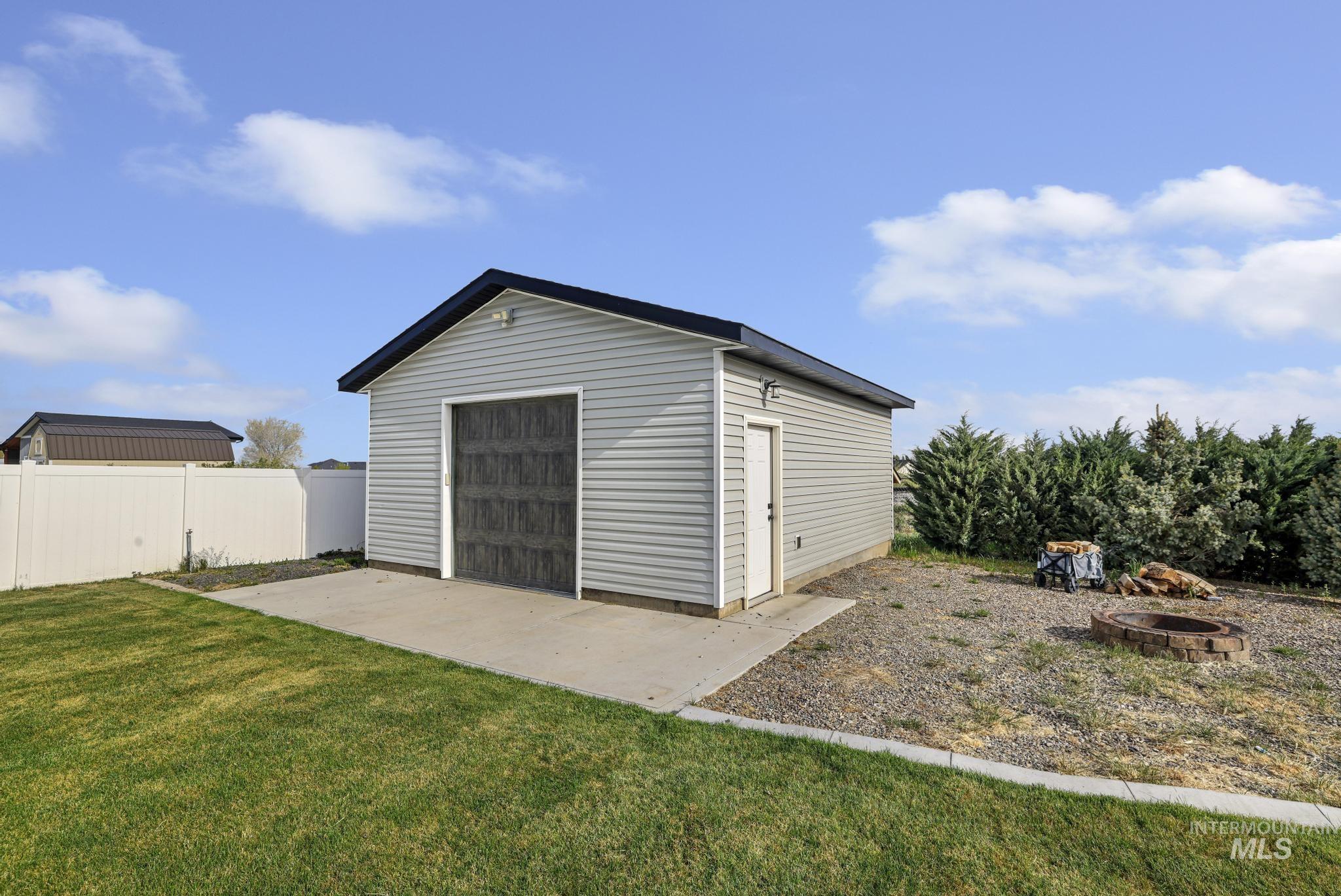 1150 Kimberly Meadows Road Kimberly, ID 83341 - Photo 28 of 32 Detached accessory building featuring light gray siding, dark roofline, a garage door, and a side entry door