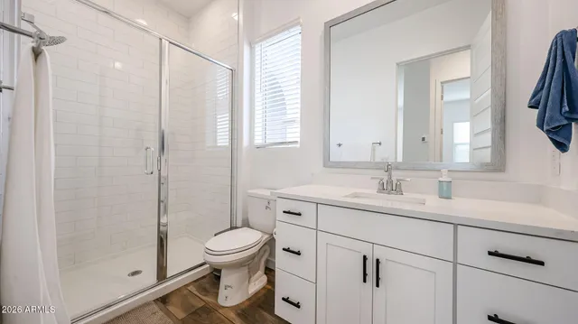 a bathroom with a toilet sink vanity granite and shower