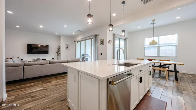 a kitchen with stainless steel appliances a stove a sink a microwave oven a refrigerator and white cabinets with wooden floor