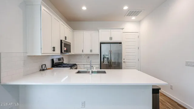a kitchen with stainless steel appliances a sink a stove a refrigerator and cabinets