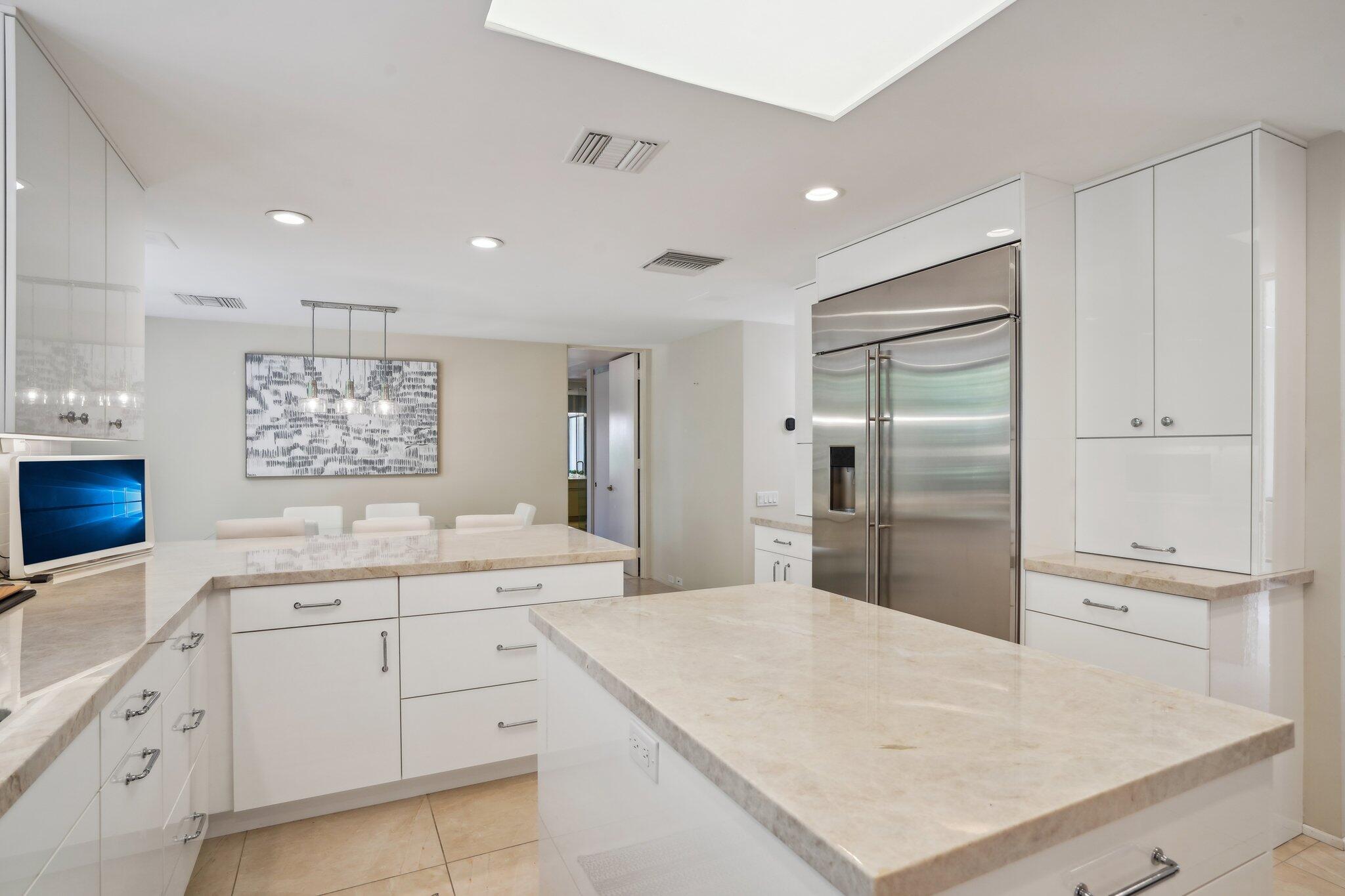 23 Park Lane Rancho Mirage, CA 92270 - Photo 24 of 57 a large white kitchen with a refrigerator a sink dishwasher and white cabinets with wooden floor