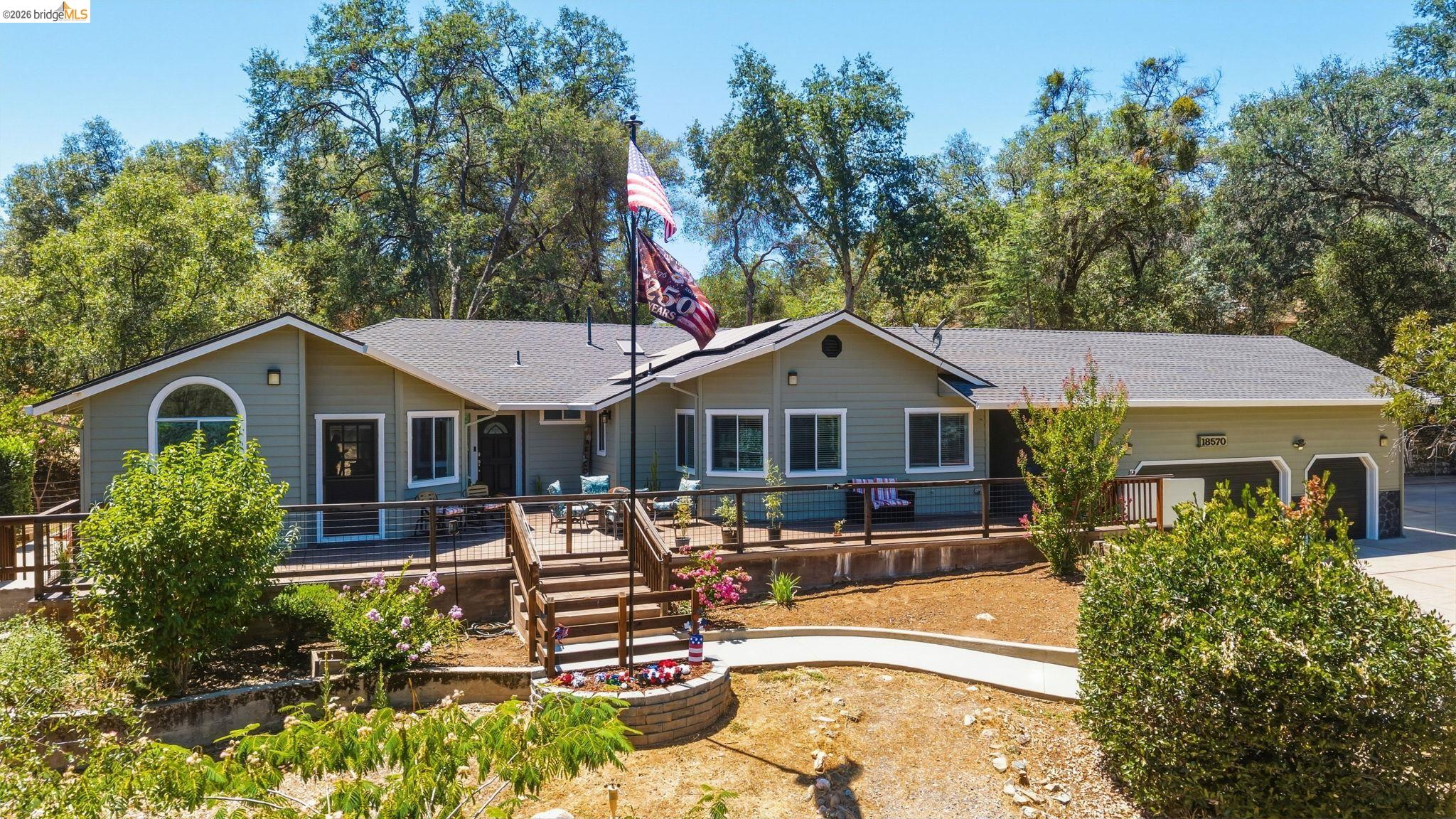 18570 Pradera Real Road Sonora, CA 95370 - Photo 59 of 66 Single-story residence featuring a covered entry, an expansive raised deck with railing, a two-car garage, and a semicircular arch window