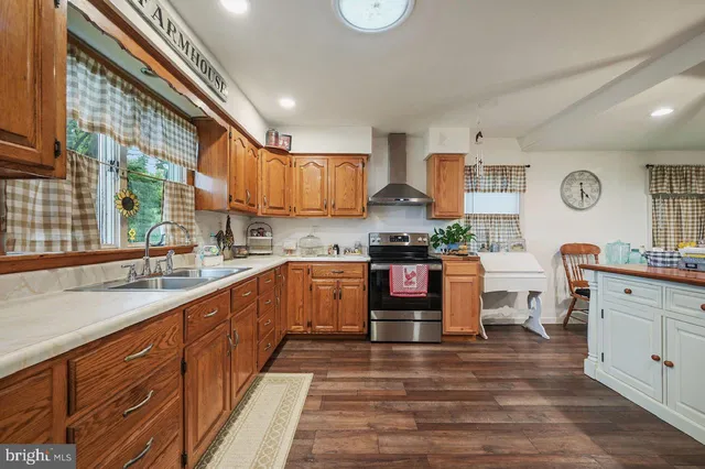 a large kitchen with a refrigerator a stove a sink dishwasher a dining table and chairs with wooden floor