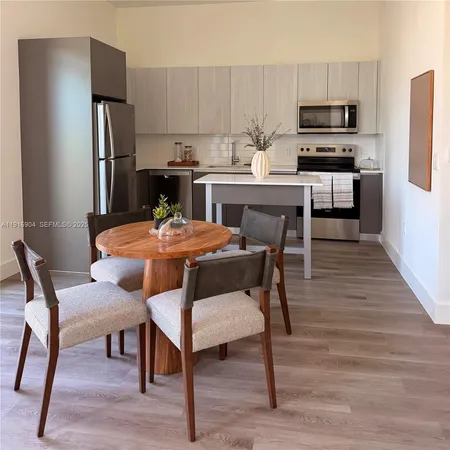 a kitchen with a dining table chairs and refrigerator