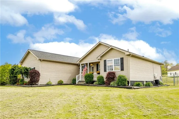 a front view of house with yard and trees in the background