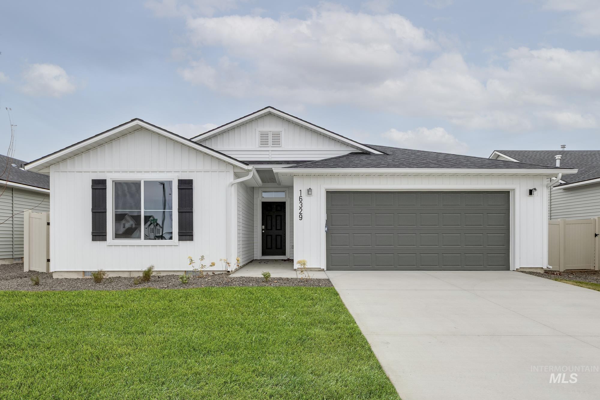View of front of home featuring a garage, driveway, roof with shingles, and board and batten siding