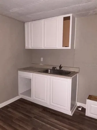 a kitchen with granite countertop wooden floors and a sink