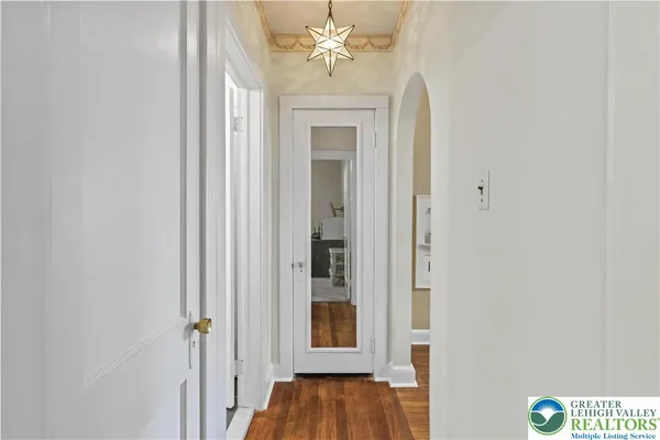 a view of a hallway with wooden floor and a chandelier