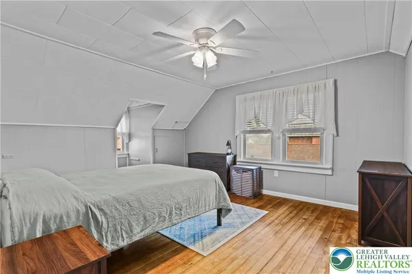 a bedroom with a bed and dresser with wooden floor