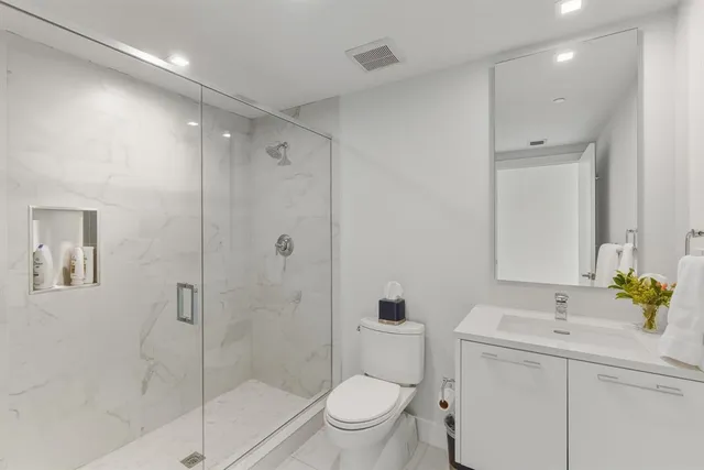 a bathroom with a toilet a sink a mirror and a shower