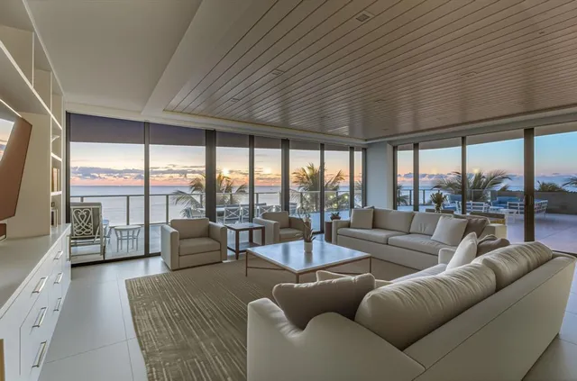 a living room with furniture floor to ceiling windows and a table