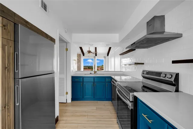 a kitchen with stainless steel appliances granite countertop a refrigerator a stove and a sink