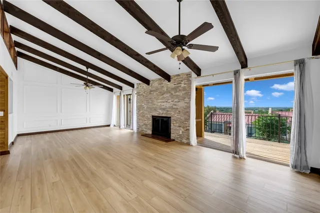a view of a livingroom with wooden floor a ceiling fan and window