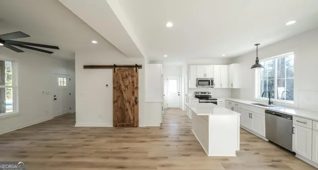 a kitchen with stainless steel appliances kitchen island granite countertop a refrigerator and a sink