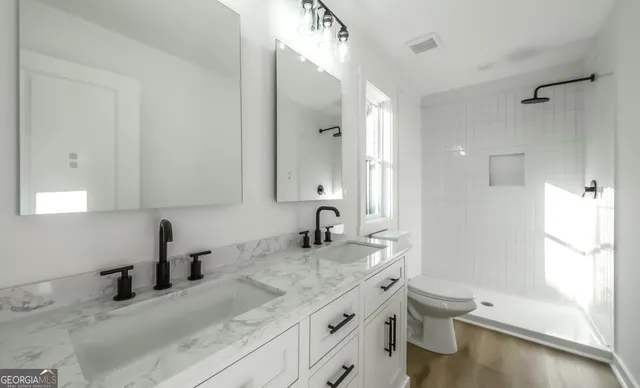 a bathroom with a granite countertop sink toilet and shower