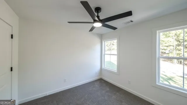 an empty room with windows and fan