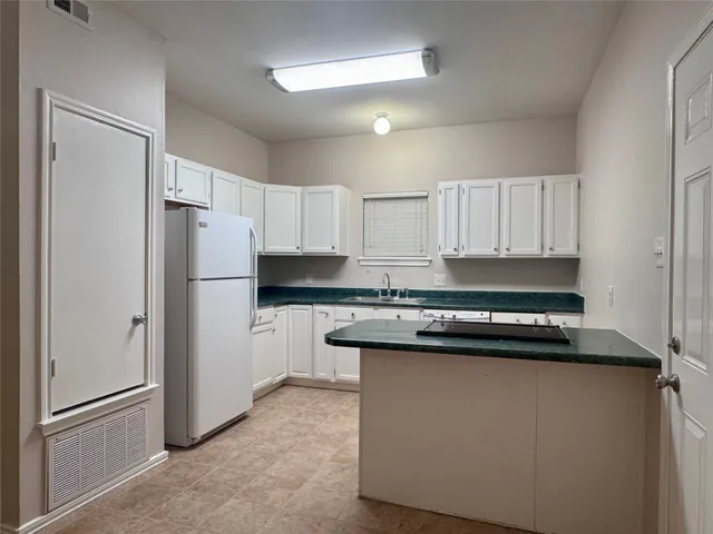 a kitchen with a refrigerator and white cabinets