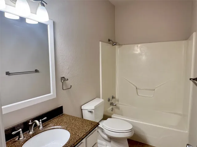 a bathroom with a granite countertop sink toilet and shower