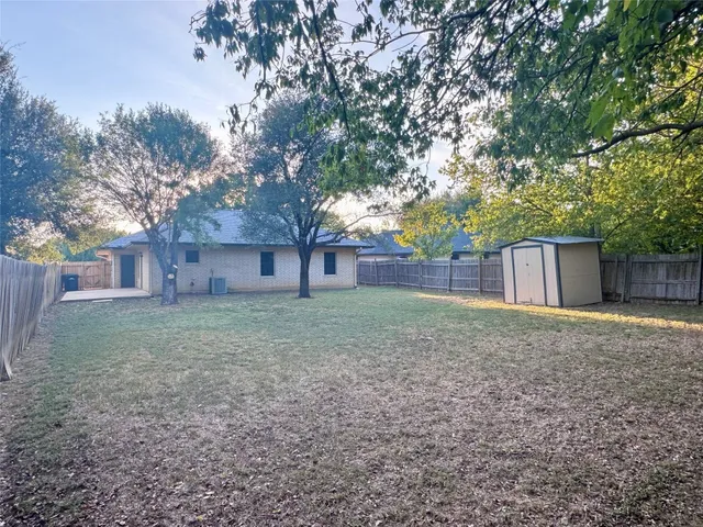 a view of a backyard with large trees and wooden fence