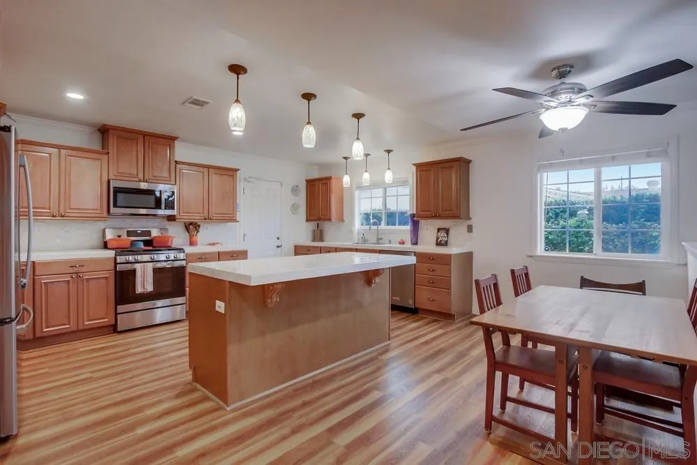 10520 El Nopal Santee, CA 92071 - Photo 2 of 34 a large kitchen with kitchen island a dining table chairs and a wooden floor