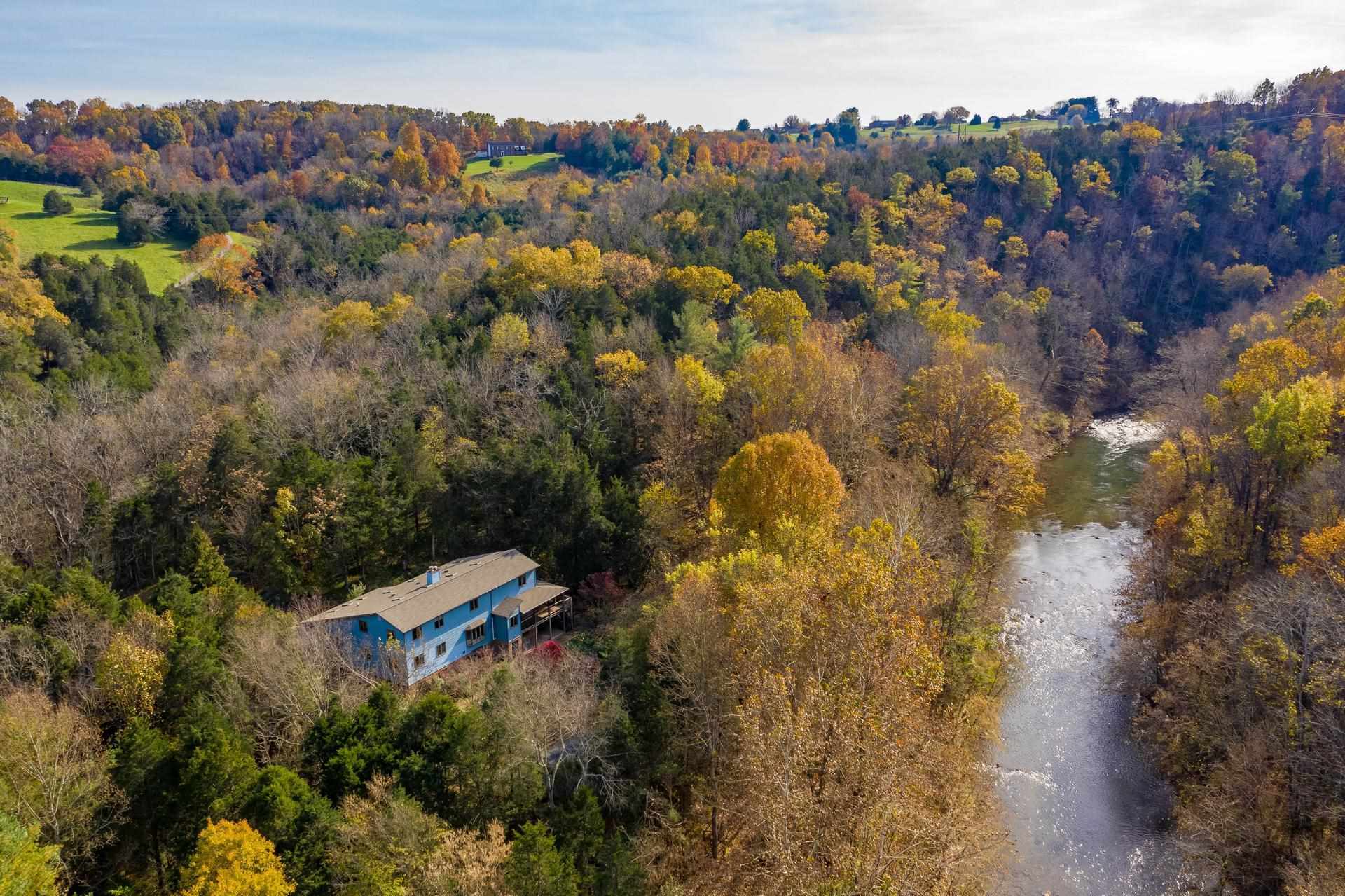 an aerial view of residential house with outdoor space and trees all around
