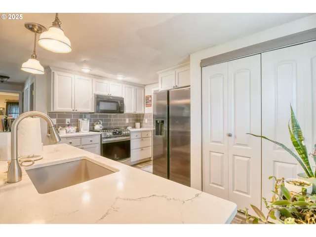 a kitchen with stainless steel appliances kitchen island granite countertop a refrigerator a sink a stove with white cabinets