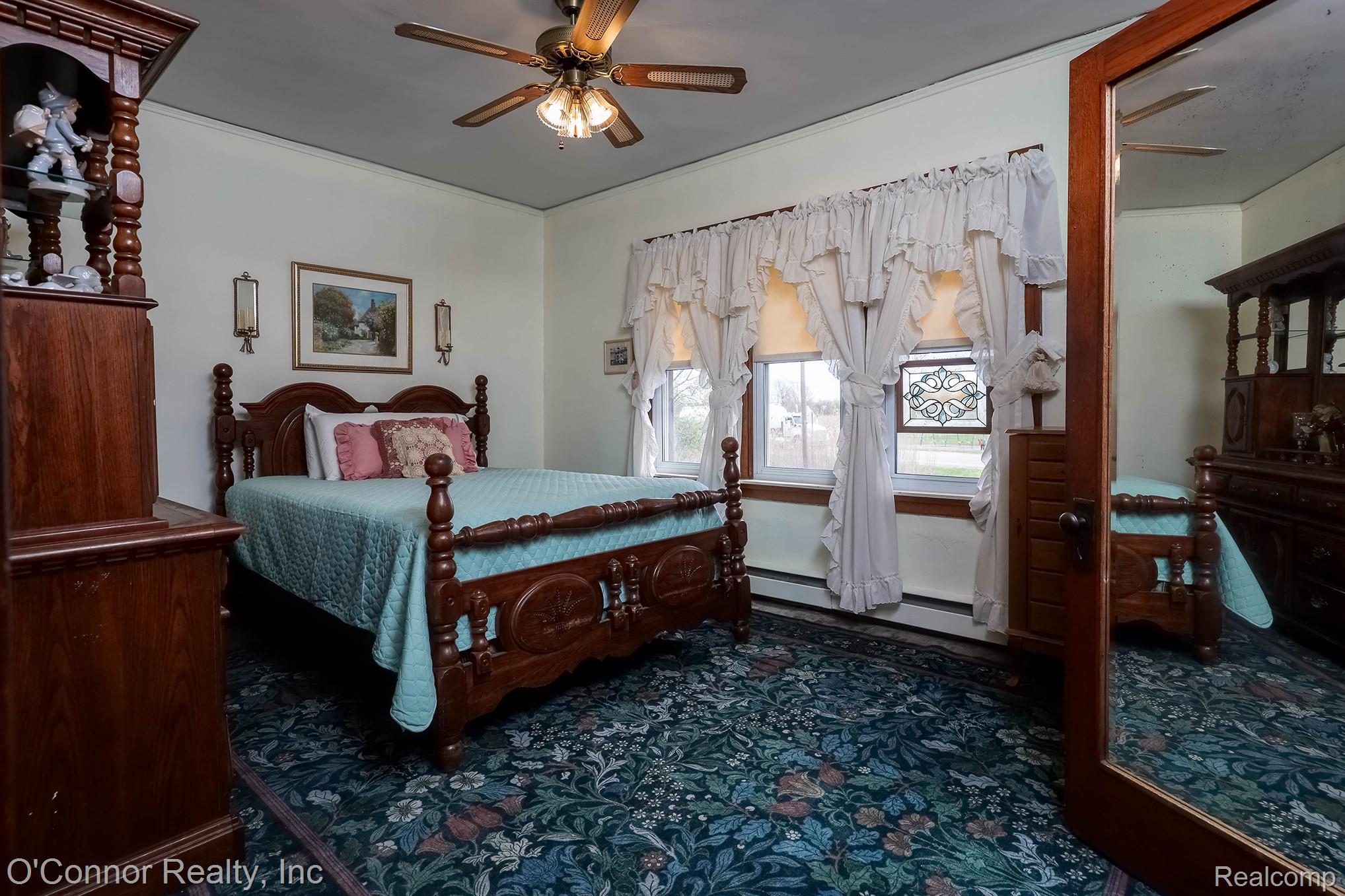 3323 Kinney Road Emmett, MI 48022 - Photo 15 of 29 Bedroom featuring patterned wall-to-wall carpeting, dual windows with a stained glass accent, and a ceiling fan with integrated lighting