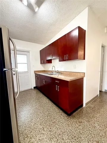 a living room with stainless steel appliances kitchen island granite countertop a refrigerator and a sink