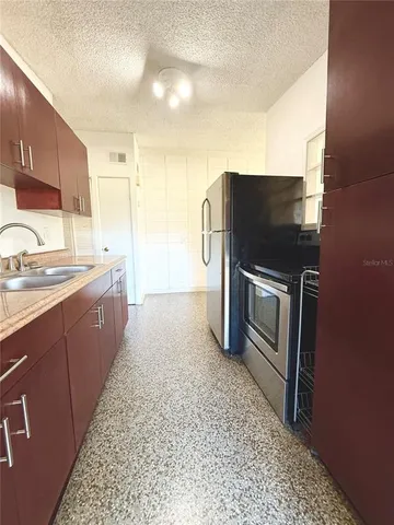 a kitchen with stainless steel appliances kitchen island granite countertop a sink stove and refrigerator