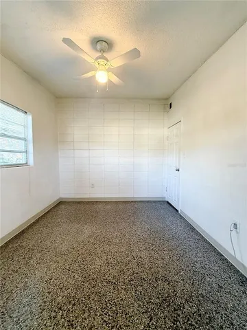 en empty room with windows and ceiling fan