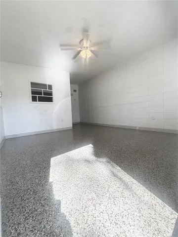 an empty room with a ceiling fan and window