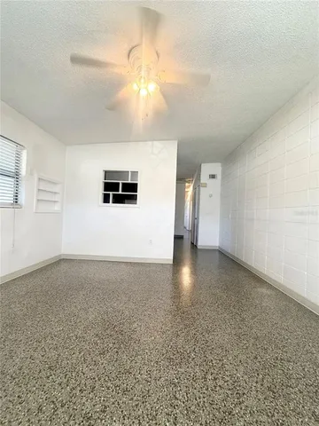 an empty room with a chandelier fan and windows