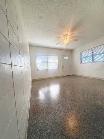 an empty room with windows and fan