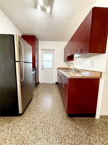 a kitchen with stainless steel appliances granite countertop a refrigerator a stove and a sink