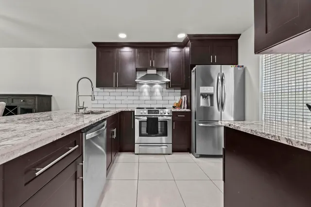 a kitchen with stainless steel appliances granite countertop a refrigerator a sink and a stove